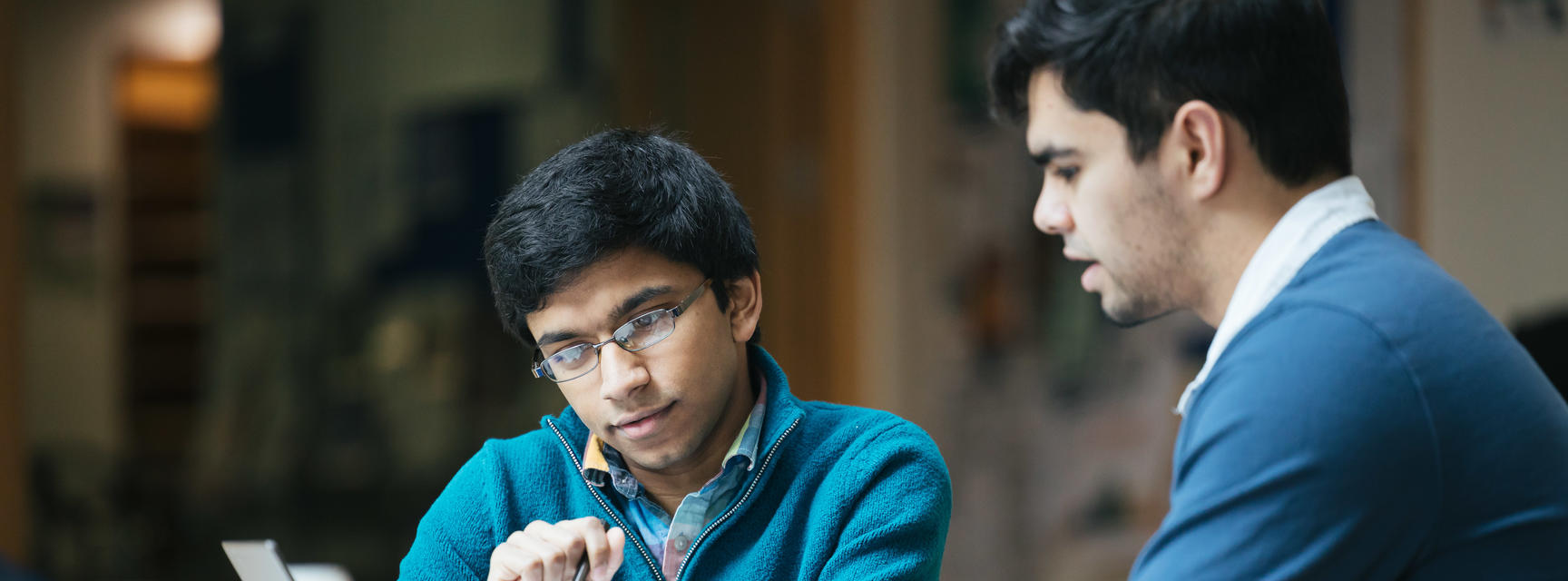 Two students work together on a laptop 