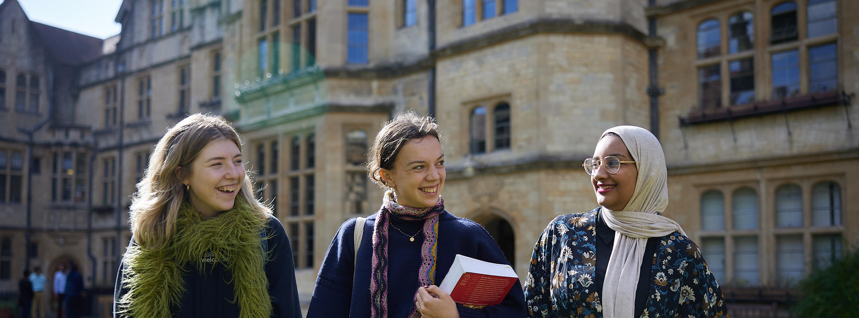 Three students walk across a college lawn in Autumn