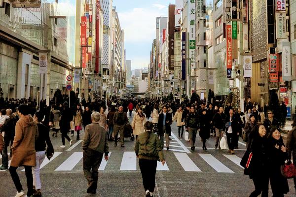 Crowds of people walk down a street lined with skyscrapers