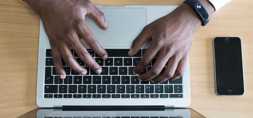 A man's hands type of a laptop keyboard