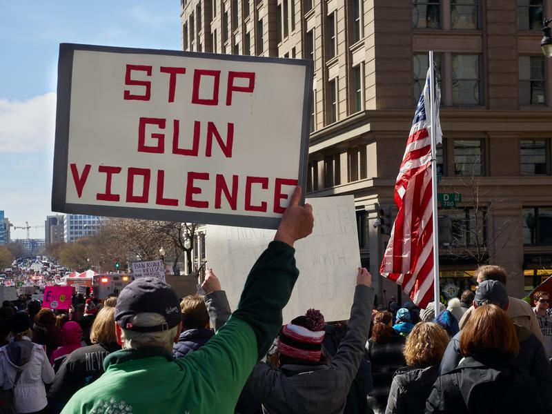 A man holds a sign saying 'stop gun violence' during a protest
