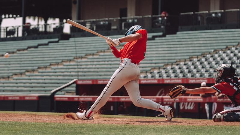 A male baseball player bats in front of an empty stadium