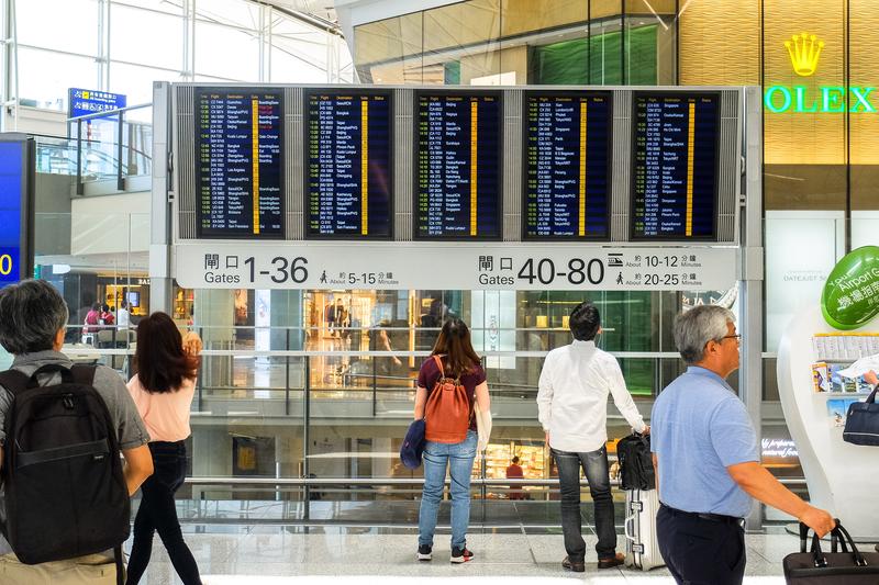 People look at a flight departure board in Hong Kong International Airport