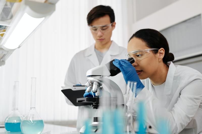 Male and female scientists look at a microscope 