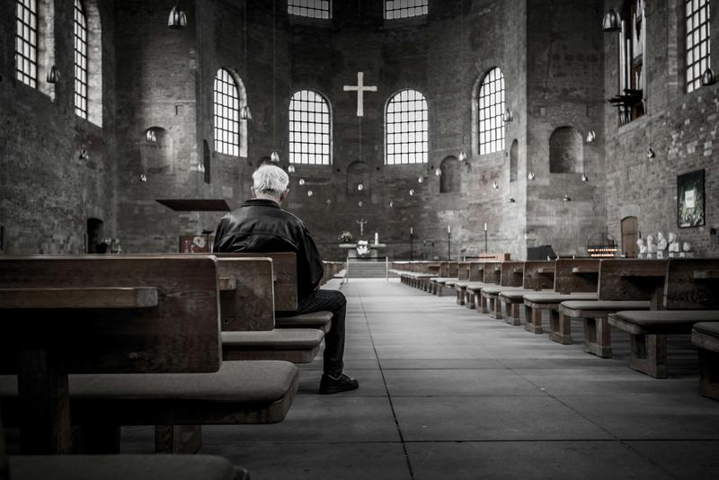 Image of lone man sitting in a church 