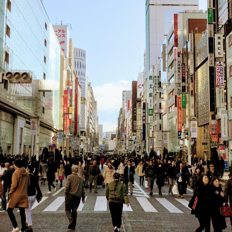 Crowds of people walk down a street in Tokyo