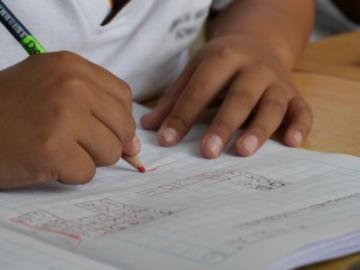 A child drawing in pencil in a notebook