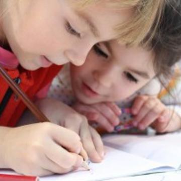 Two children writing in a school book.