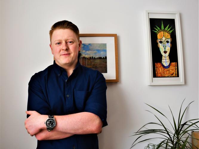 Lucas Bunnetat stands in front of two paintings