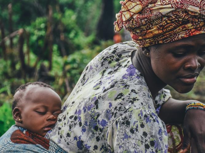 Image of a woman carrying a baby on her back