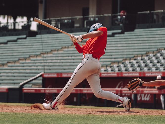 A male baseball player bats in front of an empty stadium