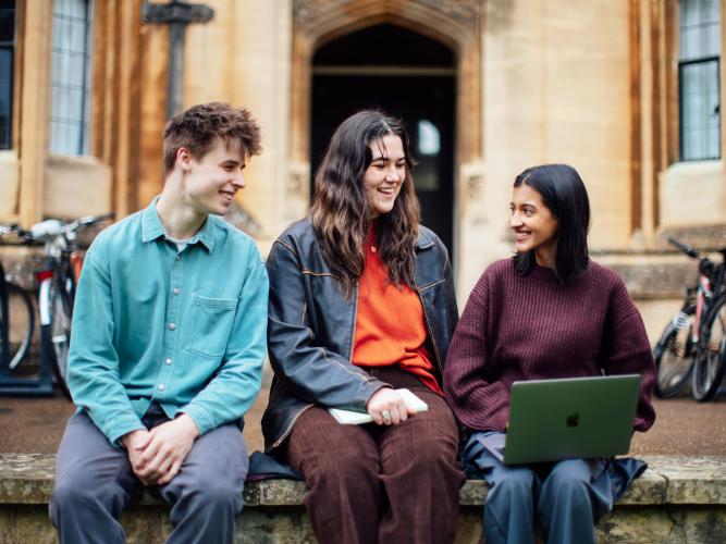 Image of three students sitting outside