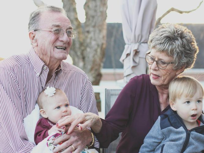 Image of an elderly couple sitting with their two young grandchildren 