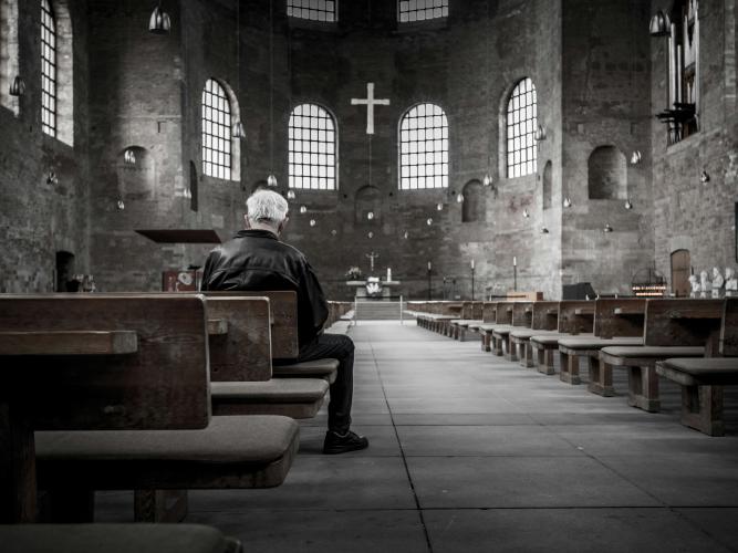Image of lone man sitting in a church 