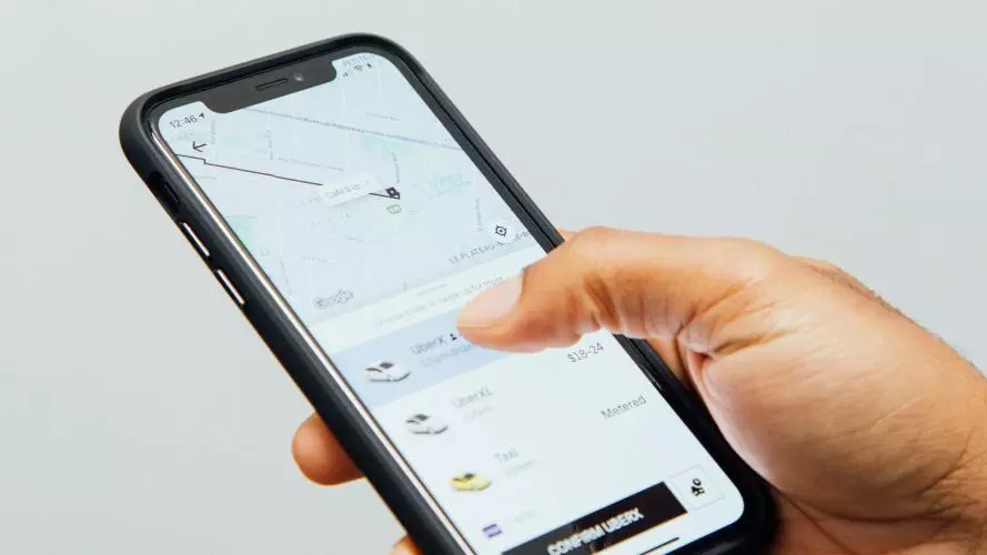 Image of a hand holding a phone showing a ride-hailing app