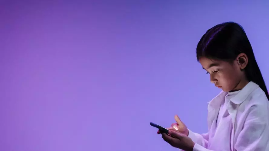 Young girl in a white shirt uses a mobile phone