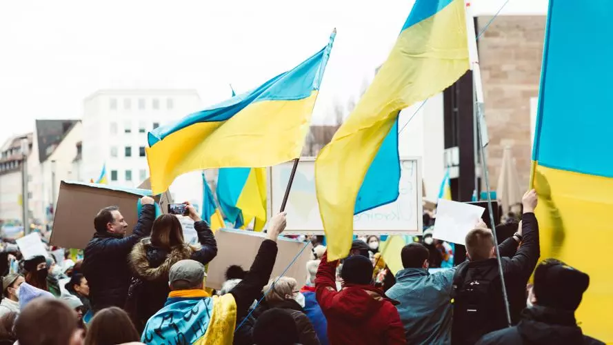 Image of people gathering on the street holding Ukrainian flags