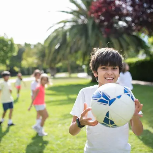 Image of boy holding an football with other children visible in the background 