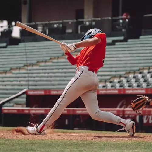 A male baseball player bats in front of an empty stadium
