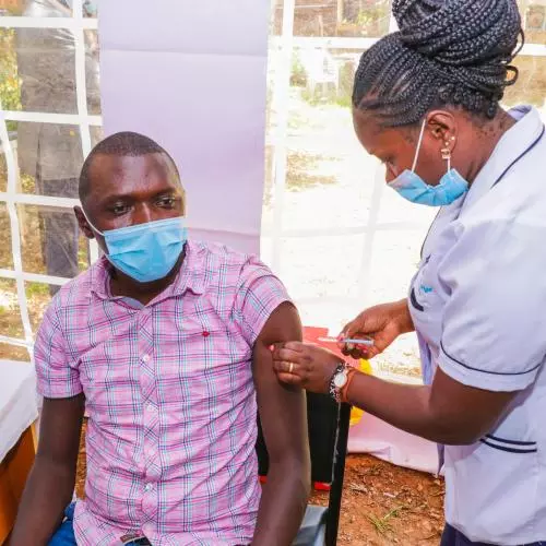 A female nurse gives a man an injection at an outdoor hospital
