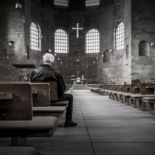 Image of lone man sitting in a church 