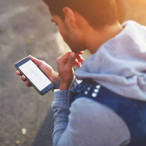 A teenager looking at a phone. Photocredit Shutterstock