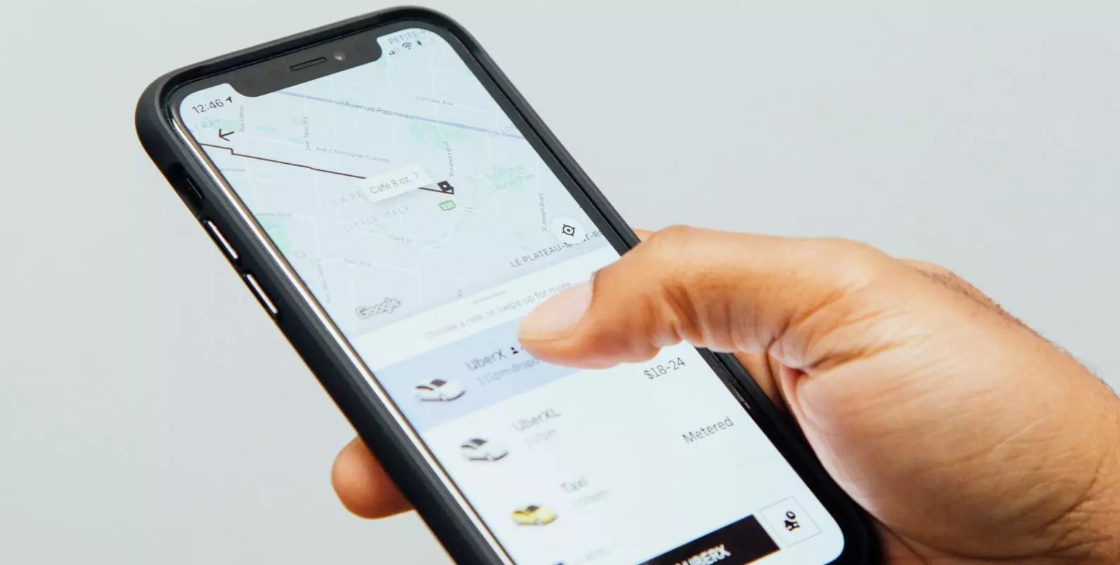 Image of a hand holding a phone showing a ride-hailing app