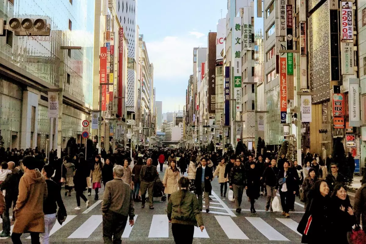 Crowds of people walk down a street lined with skyscrapers